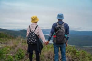 Man and woman holding hands overlooking mountains.